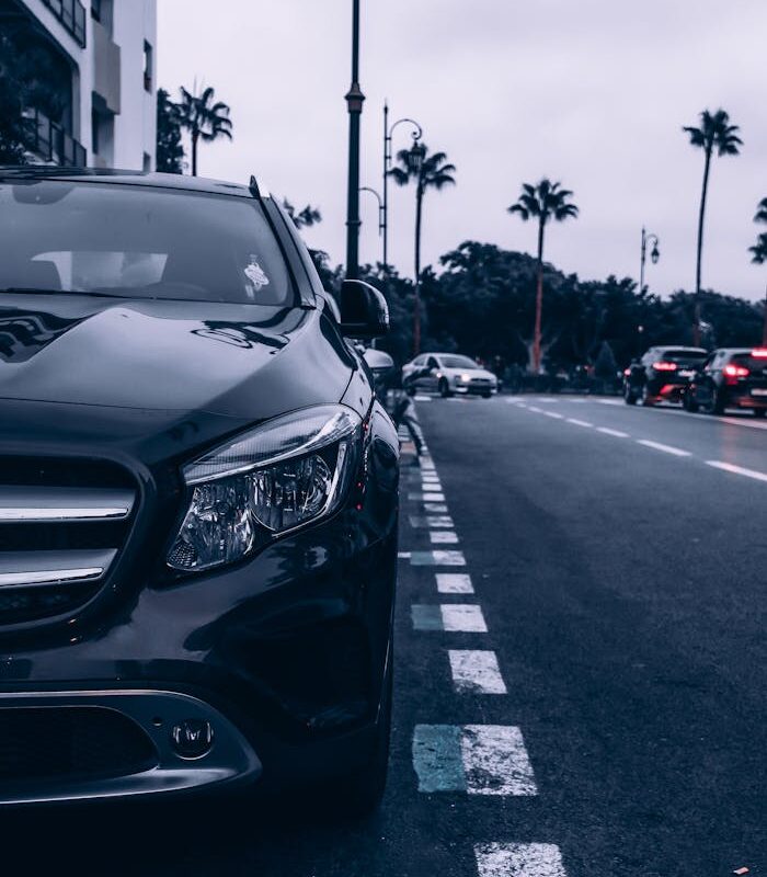 Parked car on a Rabat street with palm trees and evening lights creating an urban atmosphere.